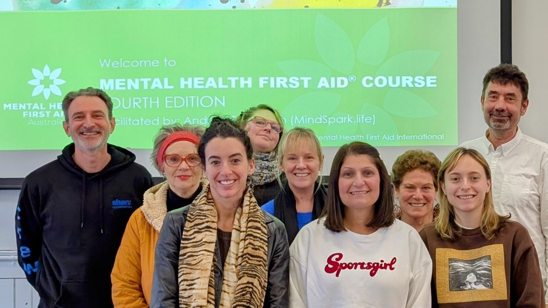 A group photo of smiling participants from a MindSpark mental health training course, representing the community feedback and testimonials.